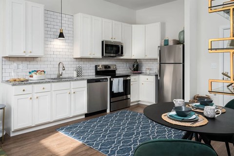 A kitchen with white cabinets and a black countertop.