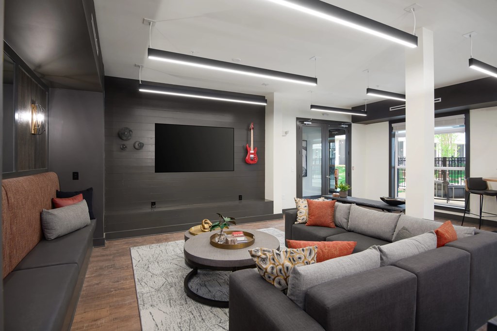 A modern living room with a grey couch and a flat screen TV mounted on the wall.