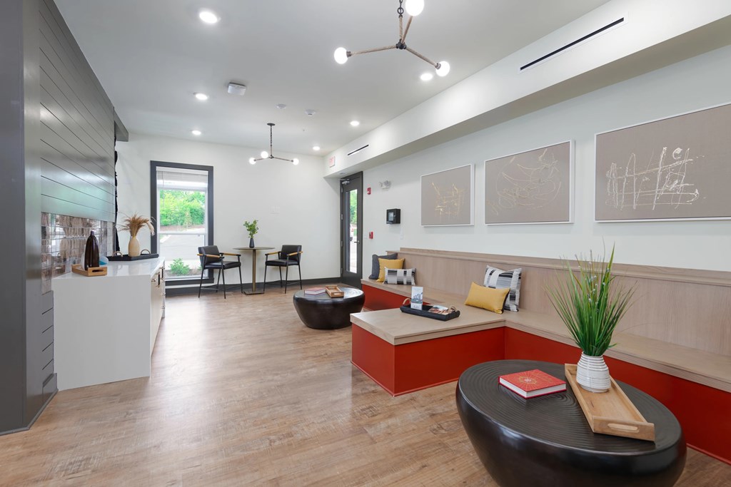 A modern office space with a black leather ottoman and a white table with a red book on it.
