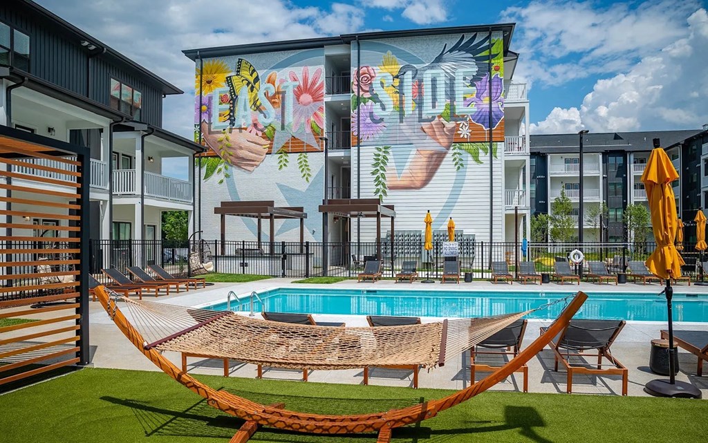 A pool area with a mural on the wall and lounge chairs.