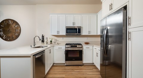 A modern kitchen with white cabinets and stainless steel appliances.