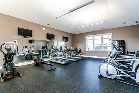 A gym with a variety of equipment including treadmills, stationary bikes, and weight machines.