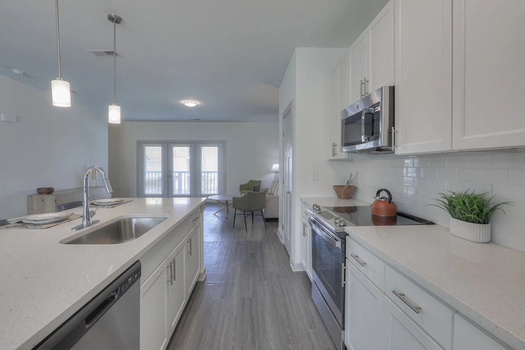 A modern kitchen with white cabinets and a wooden floor.