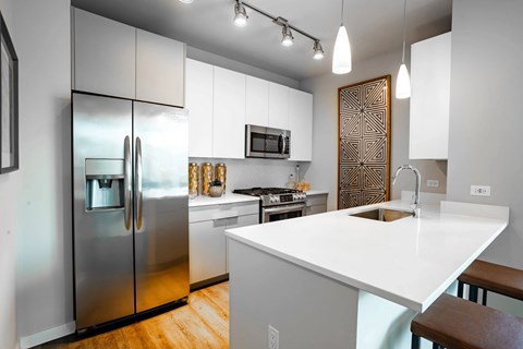A modern kitchen with a white countertop and stainless steel appliances.