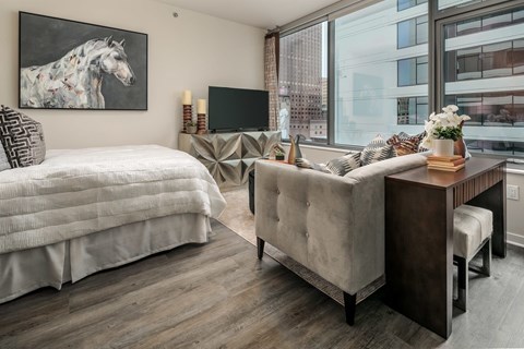 A bedroom with a large bed and a couch with a city view.