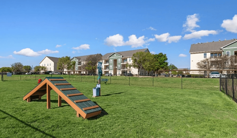 A playground with a slide in the middle of a grassy area.