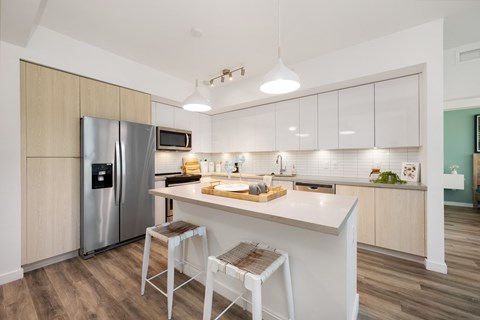 a kitchen with a large island and a stainless steel refrigerator