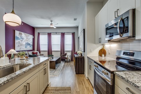 A kitchen with a purple wall and a stove top oven.