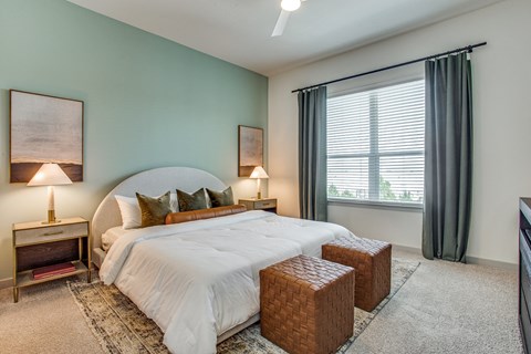 A bedroom with a large bed and two lamps.