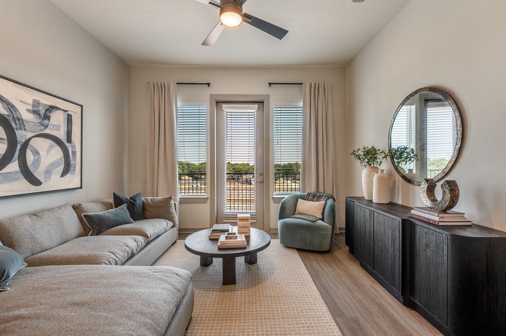 A living room with a grey couch, a green armchair, a coffee table, and a large painting on the wall.