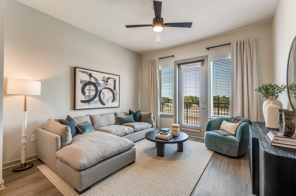 A living room with a grey sofa, a blue armchair, a coffee table, and a painting on the wall.