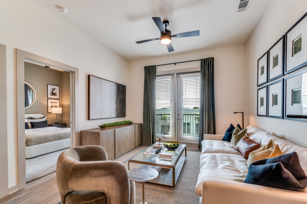 A modern living room with a large window and a ceiling fan.