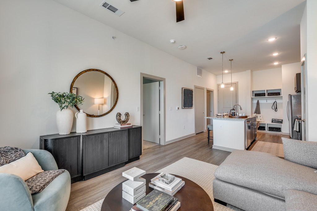 A modern living room with a grey sofa, a coffee table, and a kitchen in the background.