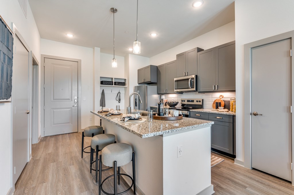 A kitchen with a white island and grey bar stools.