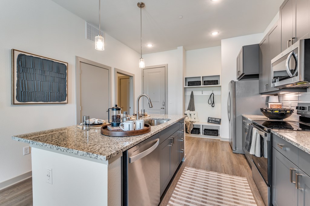 A modern kitchen with a granite countertop and stainless steel appliances.