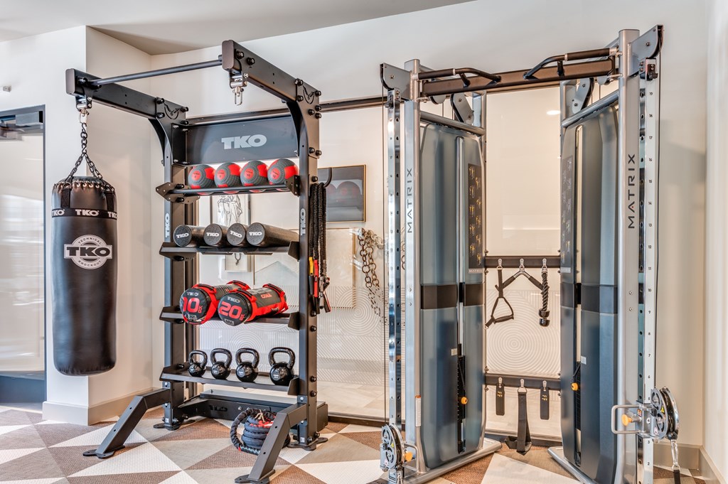 A black punching bag is hanging from a TKO branded hook in a room with a TKO branded wall.