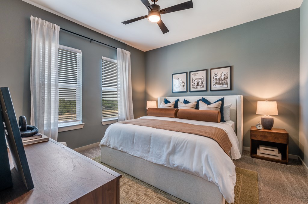 A bedroom with a large bed and a ceiling fan.
