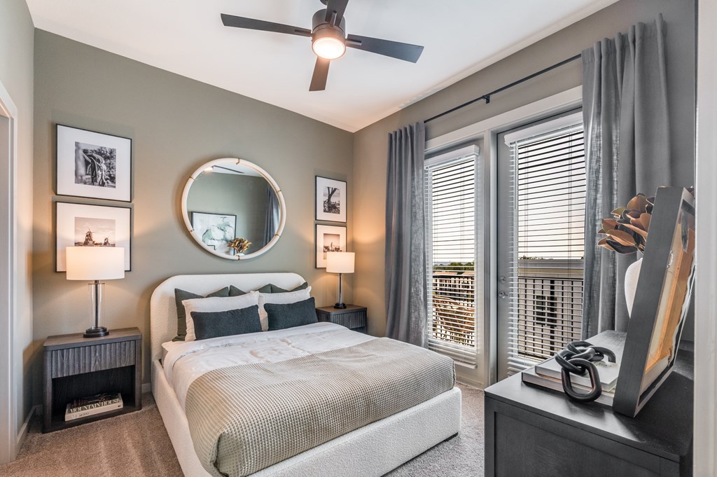 A bedroom with a large bed, a round mirror, and a ceiling fan.