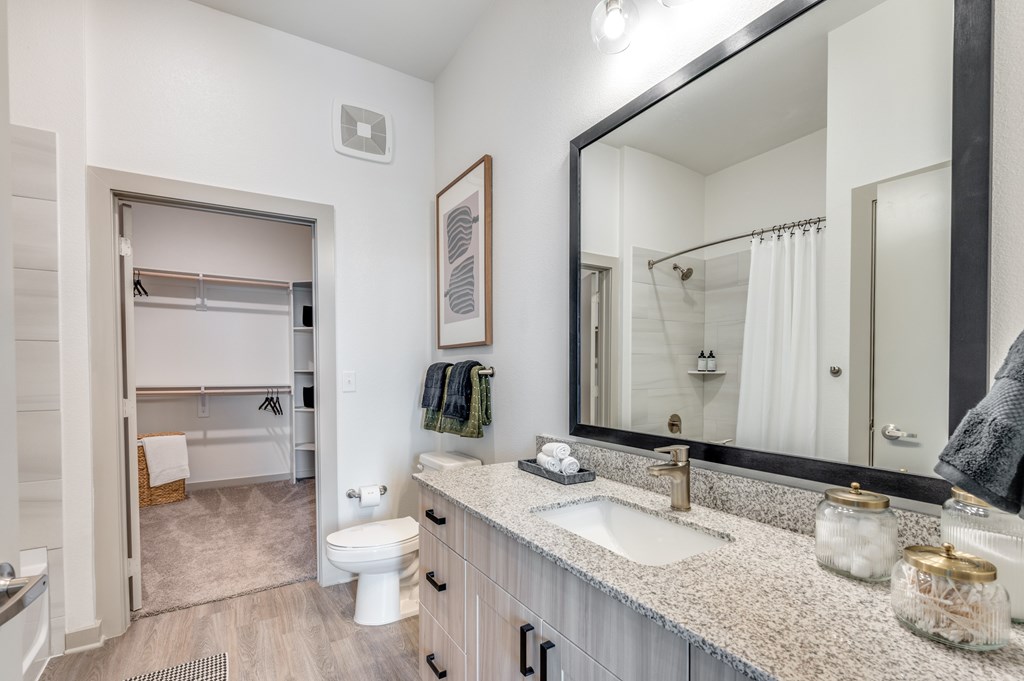 A bathroom with a white toilet, sink, and mirror.