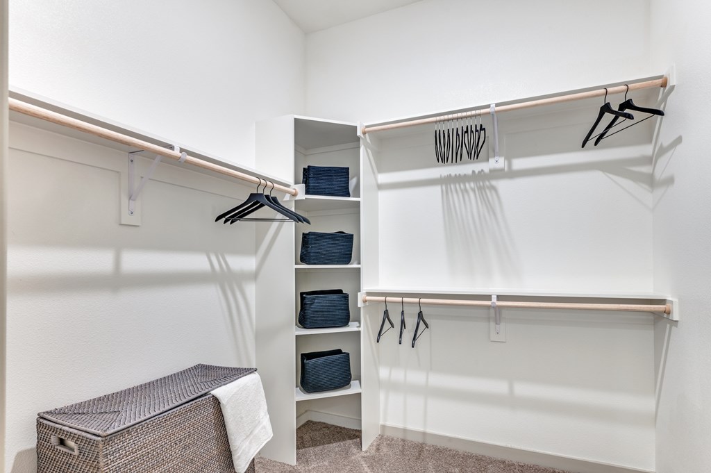 A white closet with clothes hanging and a brown box on the floor.