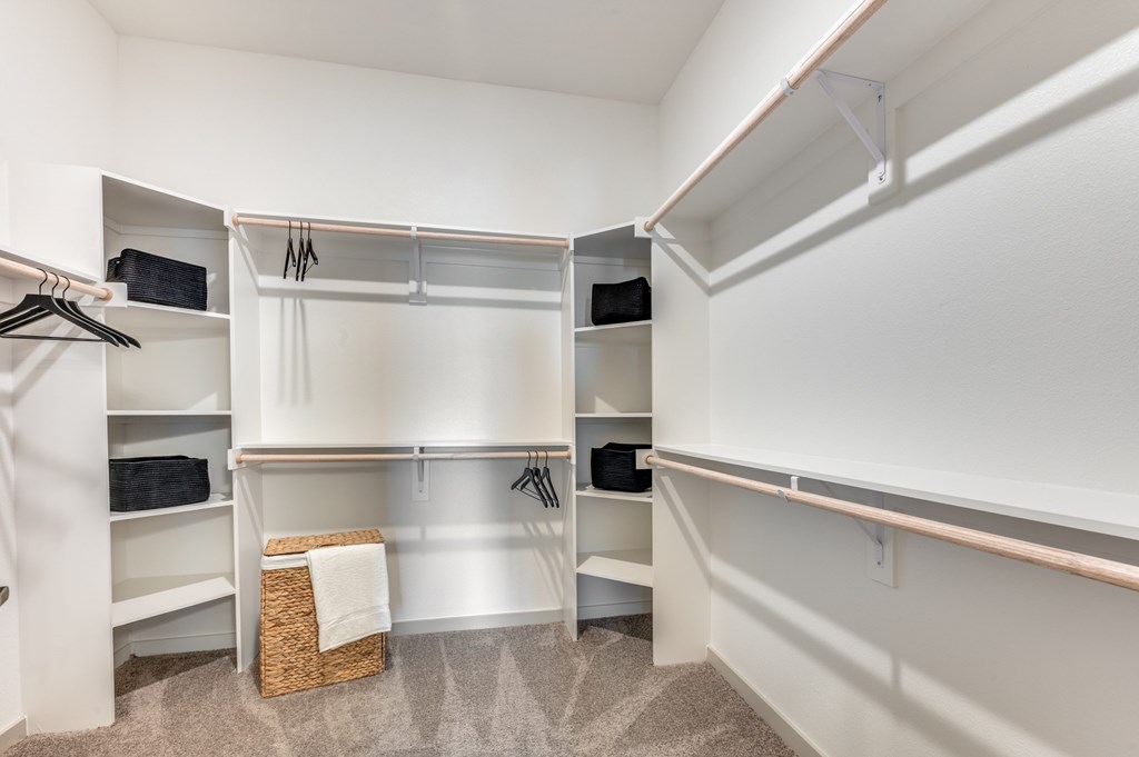 A white closet with a basket on the floor.