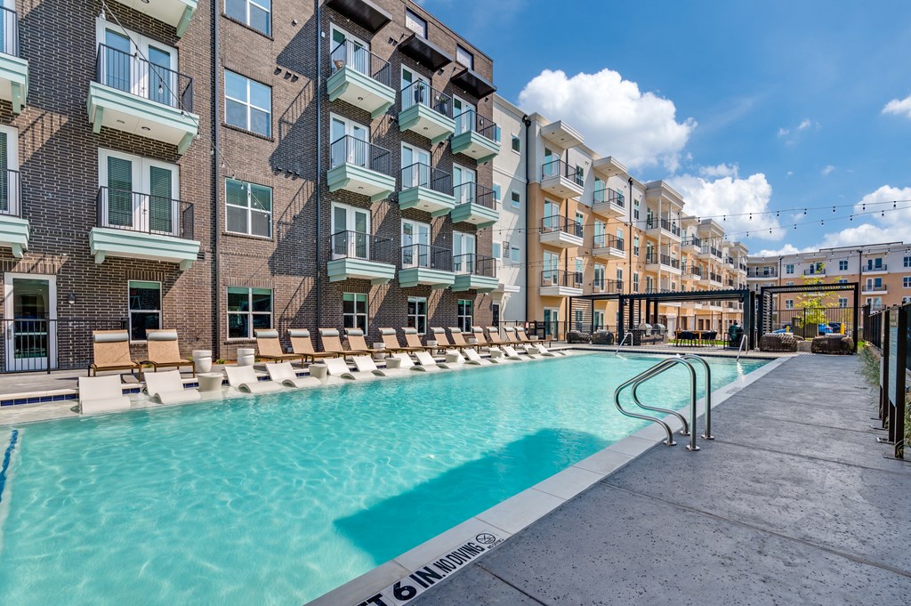 A swimming pool is surrounded by apartment buildings.