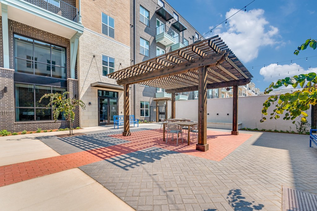 A patio with a table and chairs under a pergola.