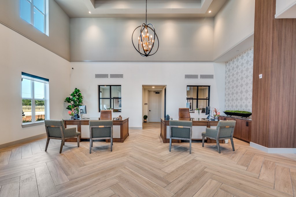 A large, well-lit room with a wooden floor and a chandelier hanging from the ceiling.