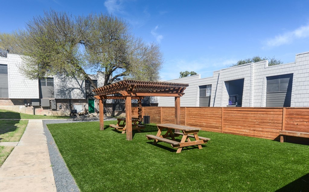 a backyard with a picnic table and a wooden fence