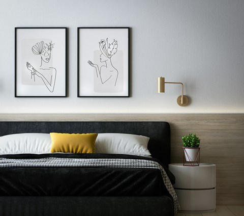 A bedroom with a black bed and two framed drawings above it.