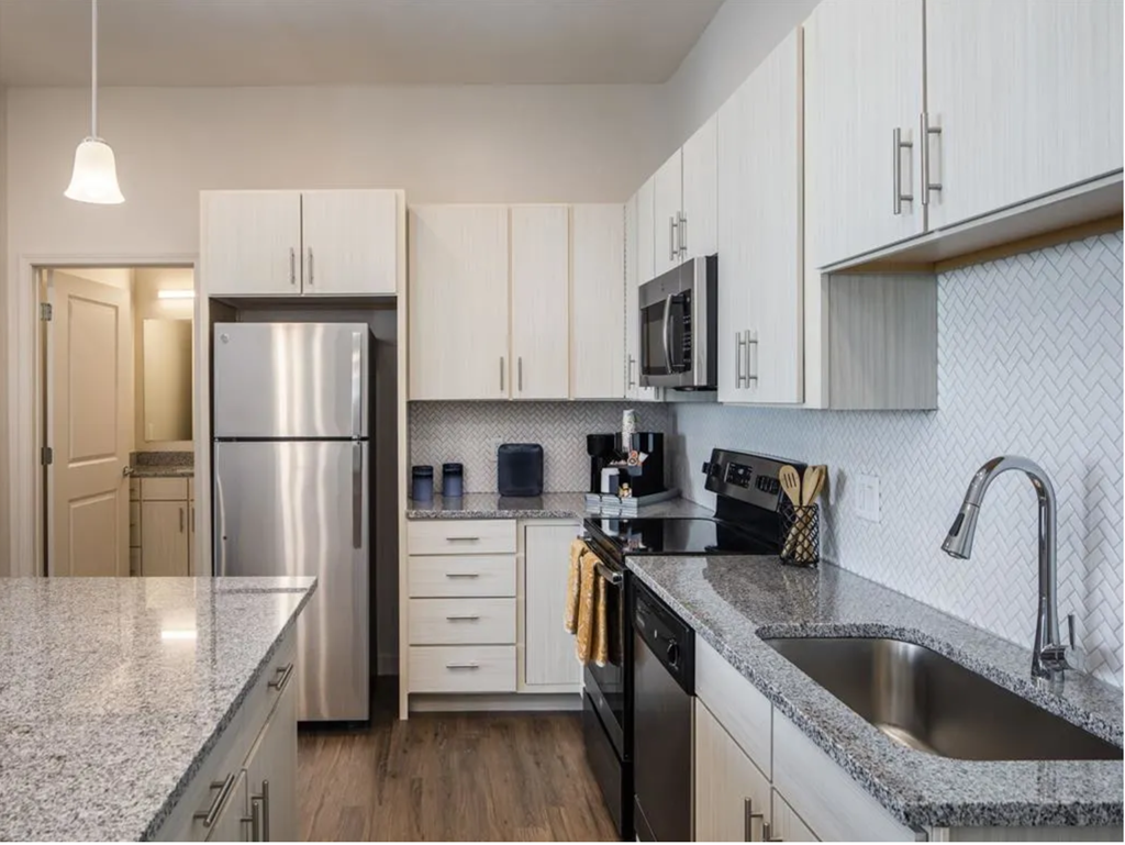 a kitchen with white cabinets and a stainless steel refrigerator