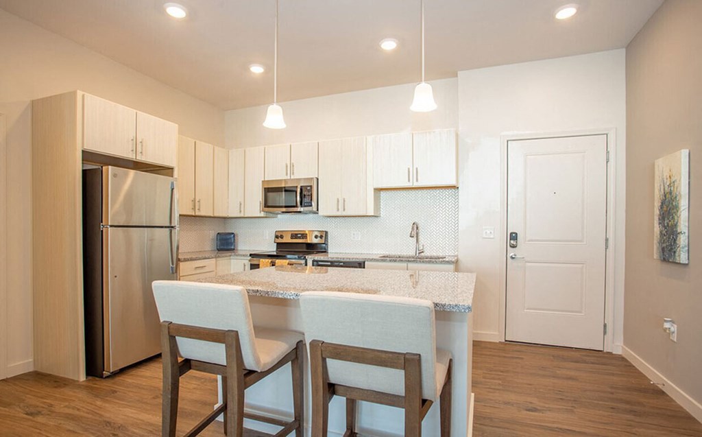 a kitchen with a marble counter top and a stainless steel refrigerator
