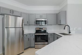 A modern kitchen with a stainless steel refrigerator and a white marble countertop.