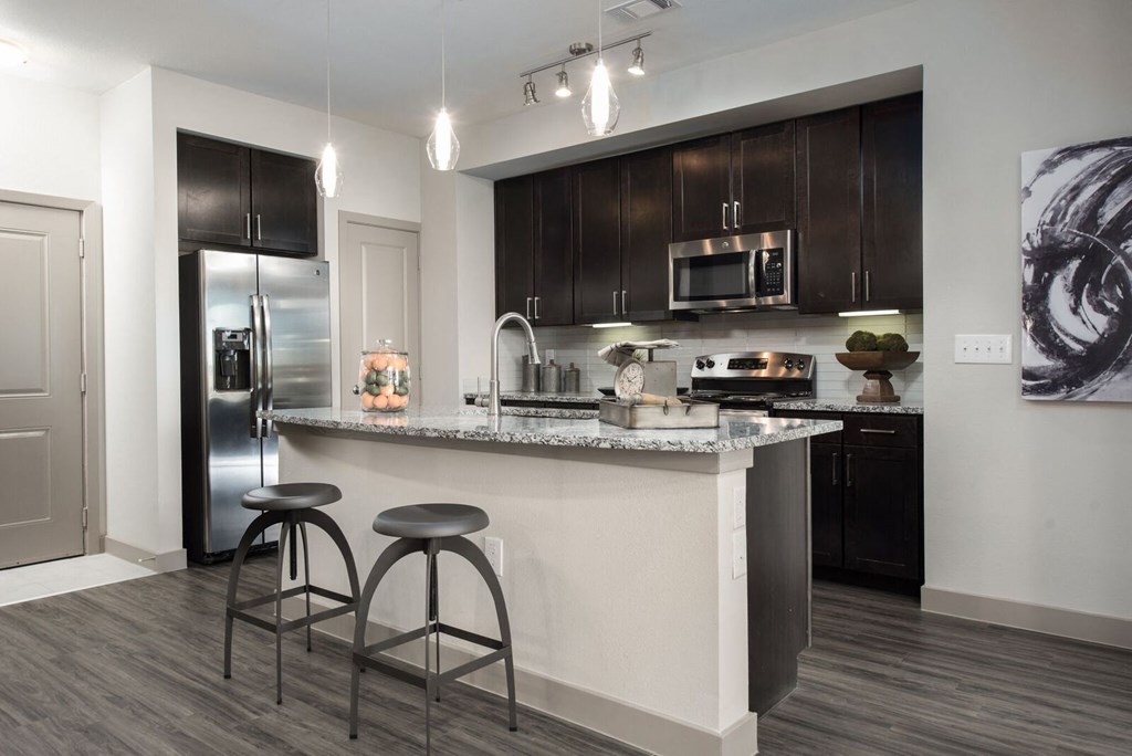 a kitchen with a large island with two stools in front of it