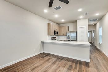 A spacious kitchen with a white countertop and wooden flooring.