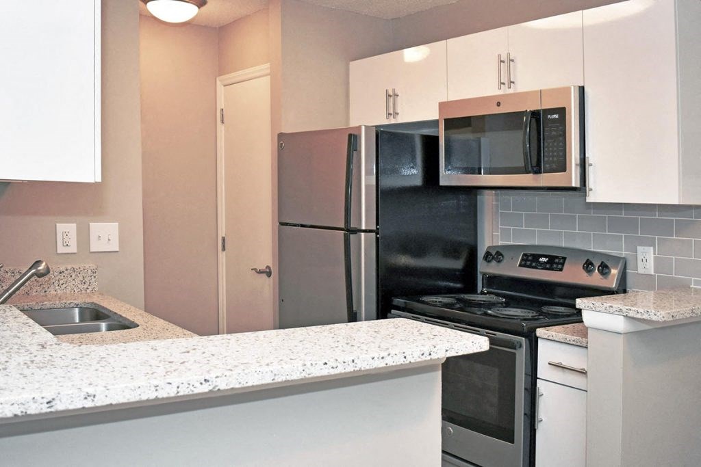 a kitchen with white cabinets and black appliances