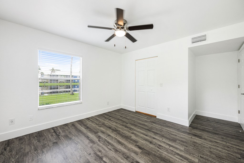 an empty living room with a ceiling fan and a window