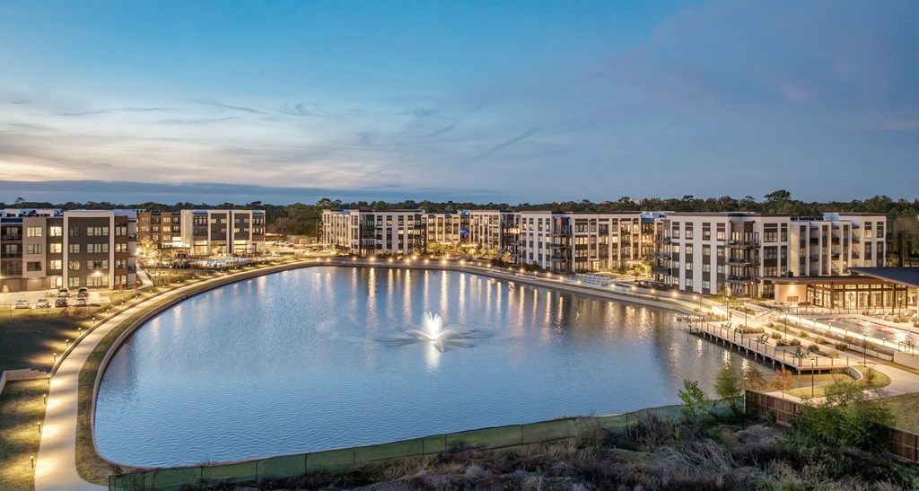 A large pool surrounded by buildings is lit up at dusk.