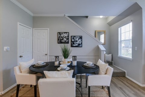 A dining room with a black table and white chairs.