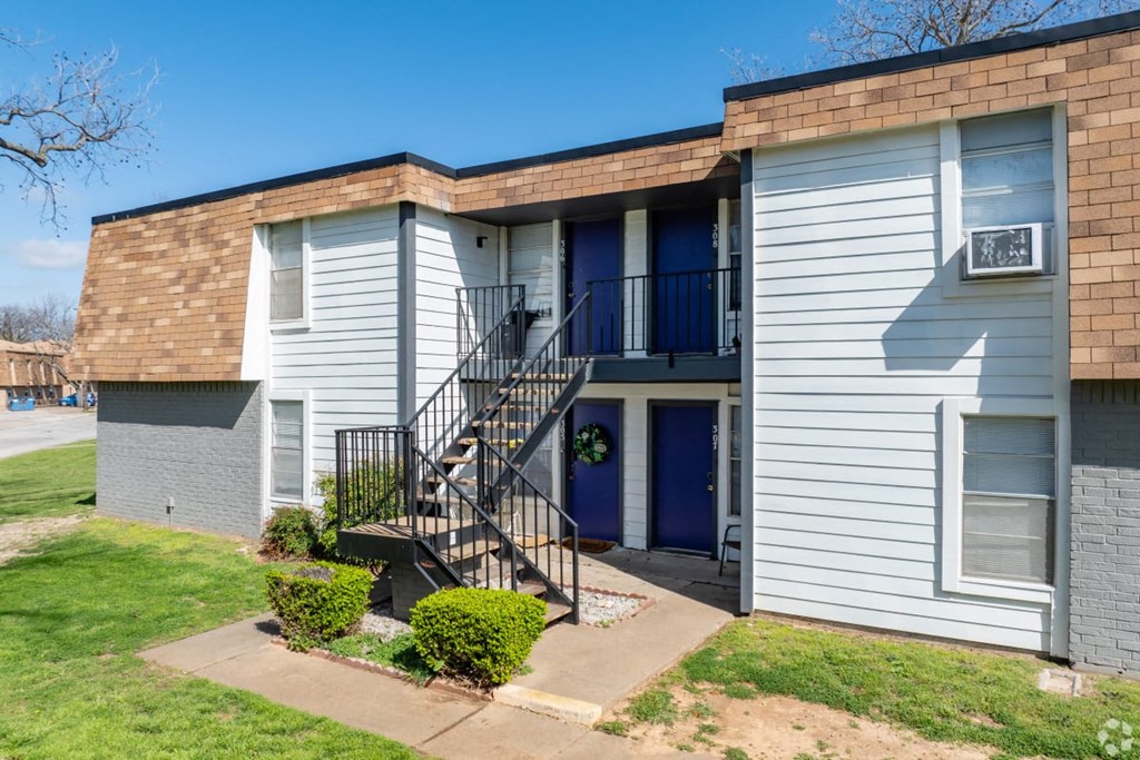 A small apartment building with a blue door and a black metal staircase.