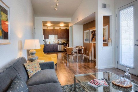 A living room with a grey couch and a glass coffee table.