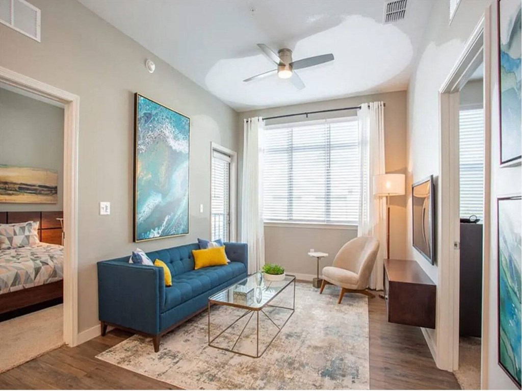 a living room with a blue couch and a ceiling fan