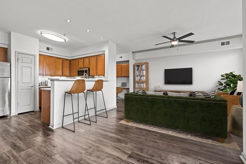 A modern kitchen with wooden cabinets and a green couch.