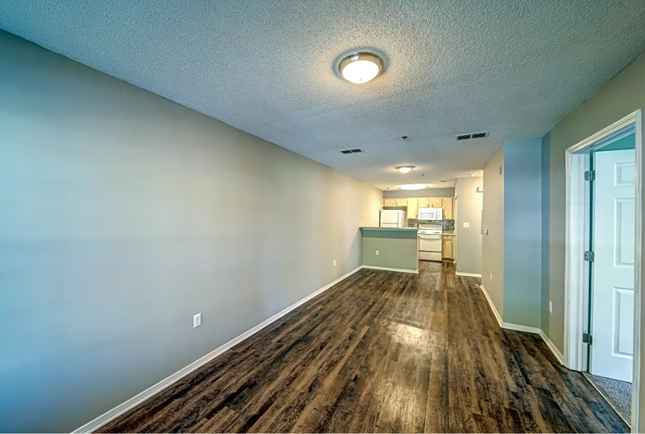 a long hallway with a wood floor and a kitchen