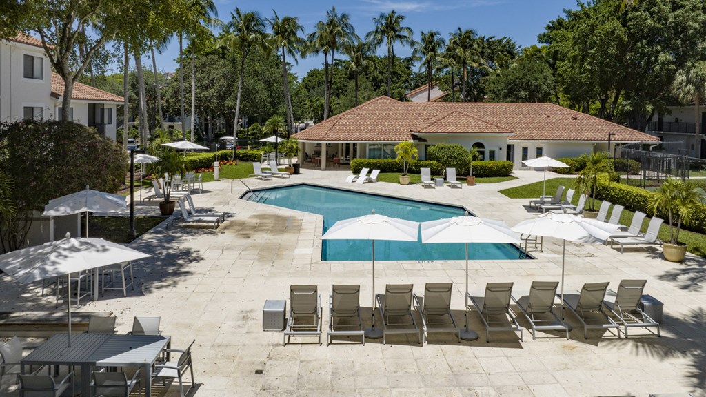 a swimming pool with chairs and umbrellas and a house in the background