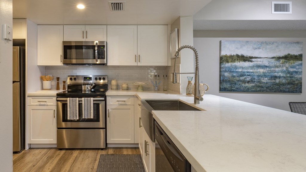 an updated kitchen with white cabinets and a marble counter top