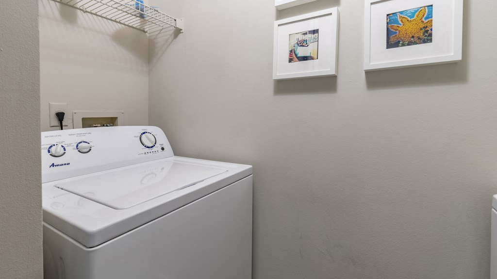 a washer and dryer in a laundry room with pictures on the wall