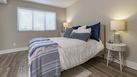 a bedroom with a bed with blue and white sheets and pillows