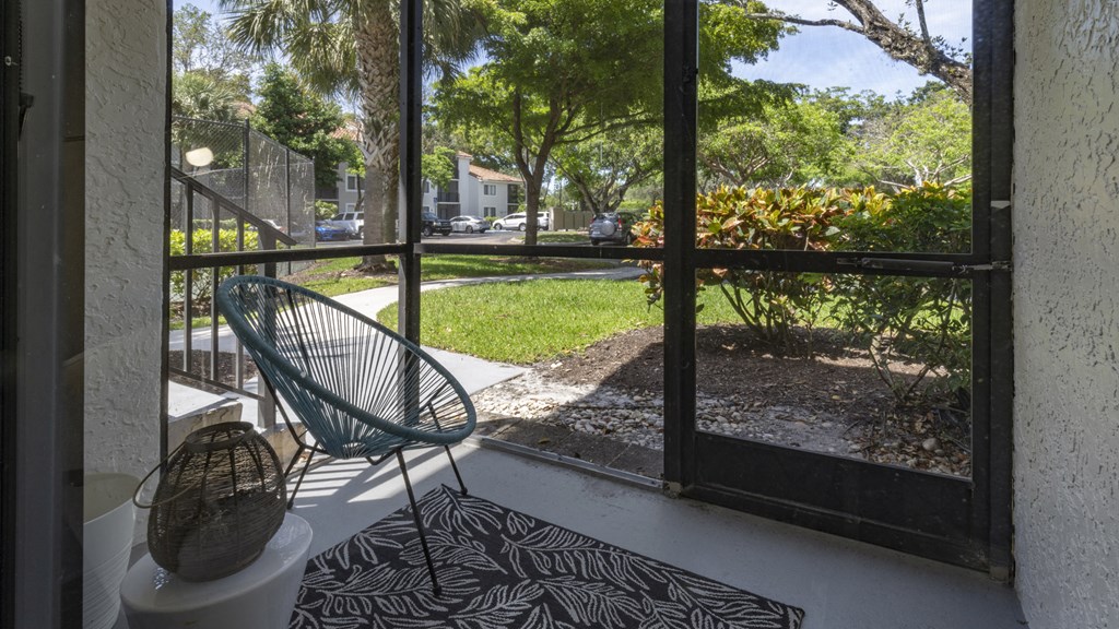 a porch with a chair and a view of the yard