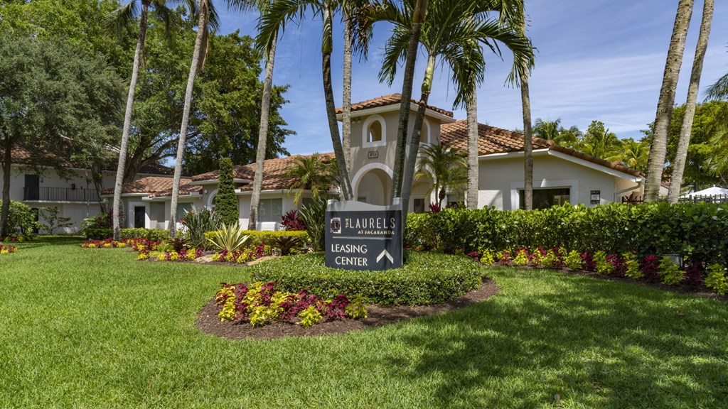 a sign in front of a house with palm trees